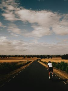 Einzelner Radfahrer auf Landstraße durch Getreidefeld