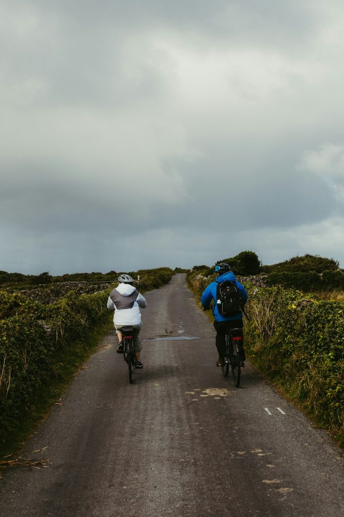 Zwei Radfahrer auf schmalem Landweg zwischen Hecken